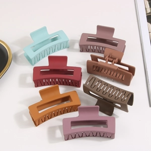 Detailed flat lay of seven colorful matte rectangular hair claws on a white background