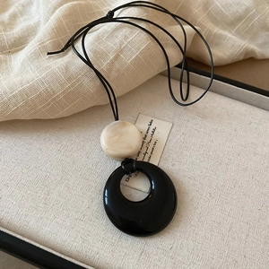 Close-up of black hollow resin pendant and cream bead in a rustic jewelry box