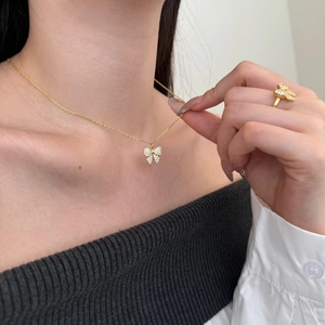 Macro detail of gold bow necklace and ring set with sparkling cubic zirconia on model