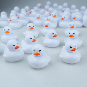 Macro shot of multiple mini white plastic ducks featuring orange beaks and black eyes