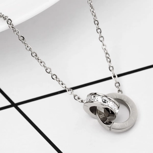 Detail view of silver interlocking double ring pendant with roman numerals and zircons