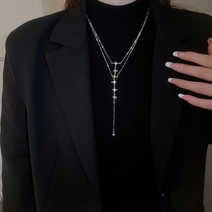 Macro shot of double-layered stainless steel star tassel necklace with crystal accents