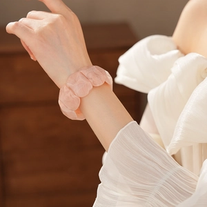 Close-up of pink faceted acrylic stretch bracelet worn by a model in a cozy setting