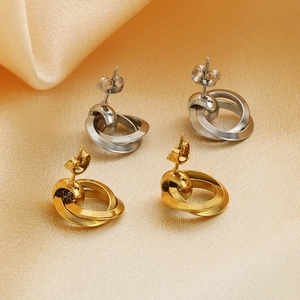 Detailed close-up of intertwined gold and silver geometric hoop earrings on silk