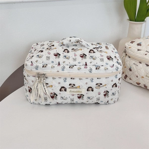 Detail of white quilted cosmetic bag with cute cartoon prints and double zipper handle