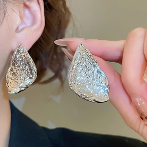 Detail of silver-tone irregular triangle earrings with a textured hammered finish on ear