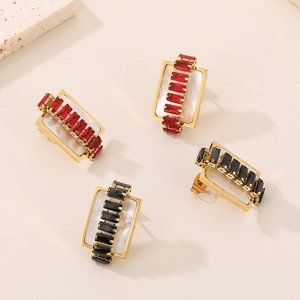 Detailed macro view of gold rectangular earrings with red and black zircon stones