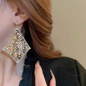 Detail view of geometric diamond-shaped earrings with gold sequins and rhinestone border