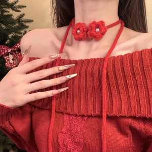 Detail of red knitted flower necklace with white pearl on festive Christmas background