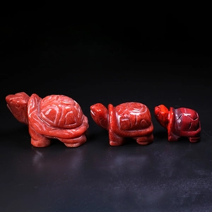 Three natural red stone turtle carvings in small, medium, and large sizes on black background