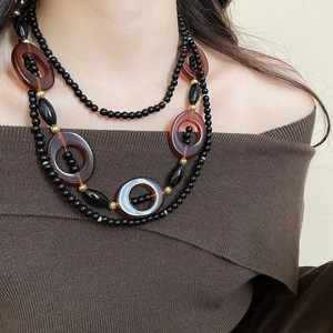 Detailed view of layered necklace with black beads and a red oval crystal pendant