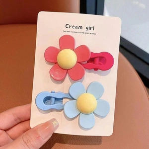Close-up of matte resin daisy hair clips in pink and blue on a display card