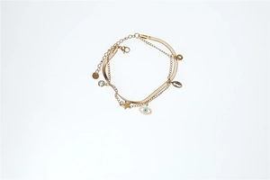 Close-up of multilayered gold bracelet with evil eye, star and zircon charms on white background