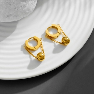 Minimalist gold chain drop earrings with spherical pendants on a white rippled plate