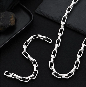 Macro shot of silver rectangular chain links with snowflake patterns and lobster clasp