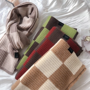 Close-up of thick knitted checkered scarves in four assorted warm color palettes