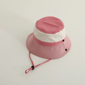 Close-up of pink and beige bucket hat featuring fabric texture and side button detail