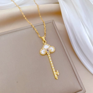 Elegant gold key necklace with white enamel and sparkling crystals on a silk background