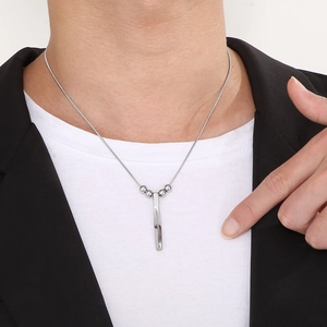 Close-up of a silver stainless steel spiral bar pendant necklace worn by a male model