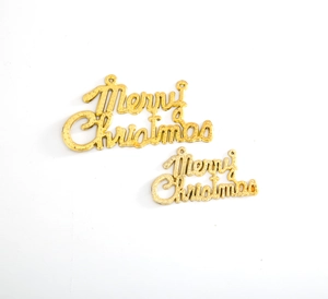 Close-up of golden metal Merry Christmas cake toppers with textured finish and hanging holes