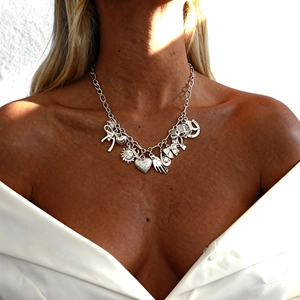 Silver multi-pendant necklace with heart and sun charms worn by a model in sunlight