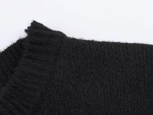 Gros plan sur l'encolure en maille et les coutures d'épaule de cet ensemble noir