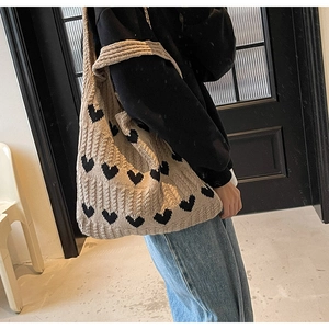 Detalle del bolso de punto con estampado de corazón negro sobre hilo beige y textura