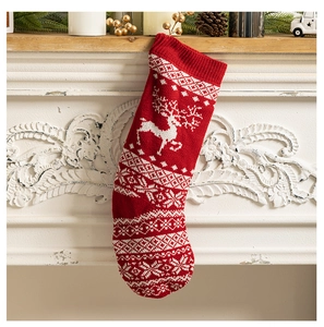Detail of red knitted Christmas stocking with white deer and snowflake patterns hanging on mantel