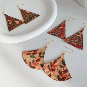 Detail of vintage cork earrings with geometric prints and gold hooks on a white plate