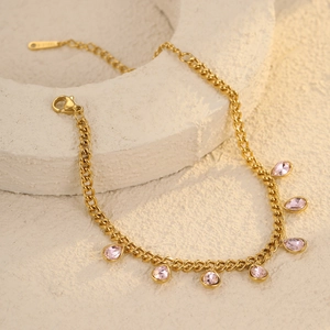 Macro shot of gold Cuban chain with pink teardrop charms and S.STEEL hallmark tag