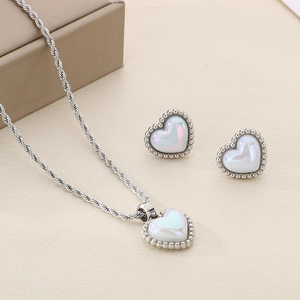 Elegant heart shell pendant necklace and stud earrings set on a textured beige surface