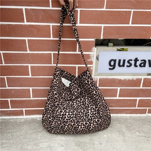 Large capacity leopard print canvas tote bag carried by hand against a brick wall