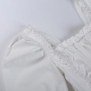 Detalle del escote cuadrado con encaje y mangas abullonadas en el vestido blanco