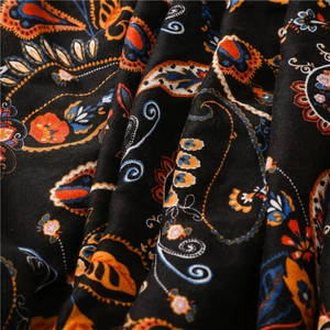 Macro shot of black paisley shawl featuring intricate orange and blue floral patterns