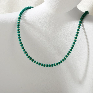 Detail of emerald green beaded necklace with gold spacers on a white bust stand
