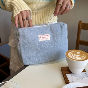 Detail of light blue faux shearling makeup bag with soft texture and white zipper