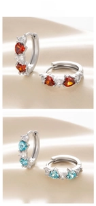 Detail of silver heart hoop earrings with red and blue zircon stones on silk