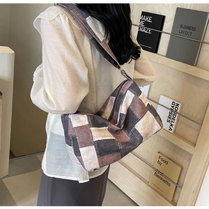 Détail d'un sac bandoulière en denim à damier patchwork porté par un mannequin de côté