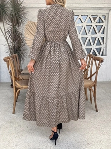 Detail of elegant brown geometric print maxi dress with tiered skirt and long lantern sleeves