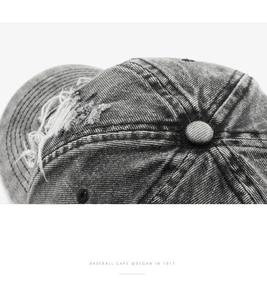 Macro detail of dark grey washed denim baseball cap with distressed rip texture