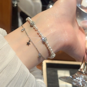 Detail shot of pearl beaded bracelet and silver star zircon chain set on a wrist