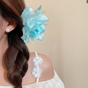 Gros plan d'une pince à cheveux fleur en tulle bleu sur un modèle pour un look de vacances.