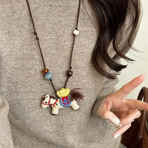 Ethnic wood resin beaded pony pendant necklace with colorful embroidery on knitted sweater