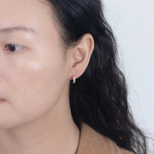 Close-up of golden geometric hexagonal zircon earrings on model's ear, minimalist style
