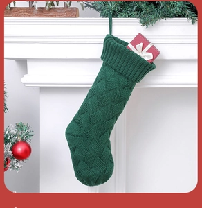 Macro shot of dark green knitted Christmas stocking with cable pattern by a fireplace
