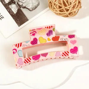 Detail of pink acrylic claw clip with colorful heart patterns on a stylish background