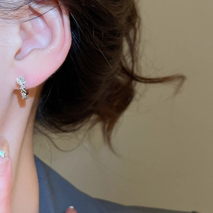 Close-up of elegant silver U-shaped earrings with sparkling cubic zirconia on model ear