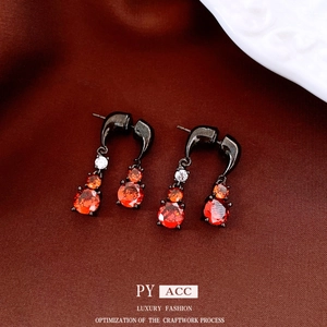Retro black metal earrings with red zircon teardrops on red silk fabric background