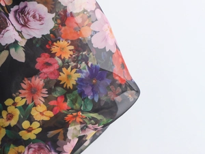 Detail of floral organza fabric with colorful rose and daisy prints on black mesh