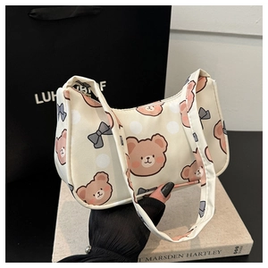 Detail of cute cartoon bear and bow print on a cream white shoulder underarm bag